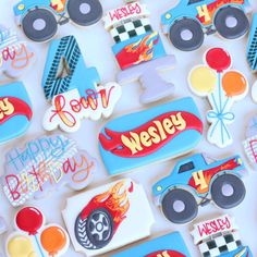 decorated cookies with cars and hot wheels are displayed on a white tablecloth that says happy birthday