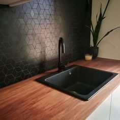 a black sink sitting on top of a wooden counter next to a potted plant