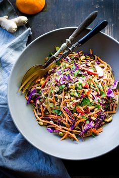 a bowl filled with coleslaw, carrots and sprouts on top of a wooden table