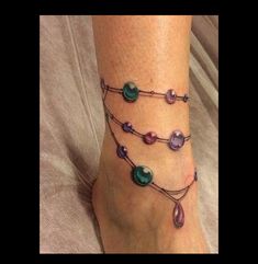 a woman's foot with beads on it and a chain attached to the ankle