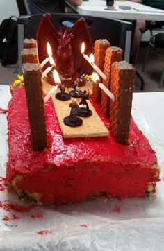 a red cake with two candles on it in the shape of a dragon and castle