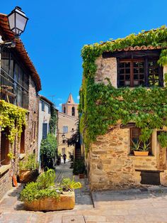 an alley way with stone buildings and plants growing on it