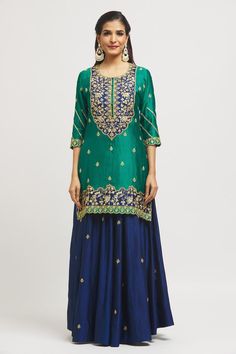 Emerald green and navy blue pure spun silk kurta with gota and marori hand embroidery. Comes with a kalidar lehenga and a pure organza dupatta.
Components: 3
Pattern: Hand embroidered
Type Of Work: Gota, Marori
Neckline: Round
Sleeve Type: Three quarter
Fabric: Pure spun silk, Dupatta: Pure organza
Color: Emerald Green
Other Details: 
Side slits on kurta
Embroidered borders on dupatta
Occasion: Mehendi and Haldi - Aza Fashions Diwali Raw Silk Sharara With Tilla Details, Navratri Art Silk Sharara With Tilla Details, Navratri Raw Silk Sharara With Tilla Details, Festive Raw Silk Sharara With Tilla Details, Festive Tilla Sharara In Raw Silk, Eid Sharara With Tilla Detailing, Eid Semi-stitched Tilla Sharara, Green Sharara With Tilla And Traditional Drape, Green Semi-stitched Traditional Wear With Tilla