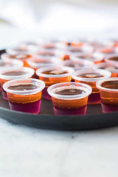 small plastic cups filled with liquid sit on a tray