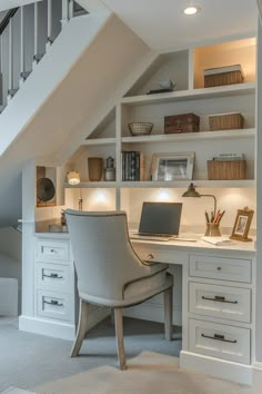 a desk with a laptop on top of it under a stair case in a home office