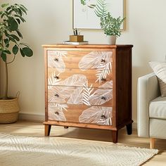 a living room with a white couch and a wooden cabinet in the corner next to a potted plant