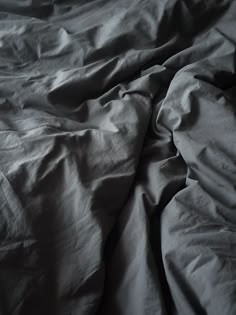 an unmade bed with black sheets and white sheets on it's sides,