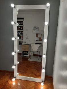 a mirror with lights on top of it in a room next to a wooden floor