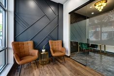 two brown chairs sitting in front of a glass wall