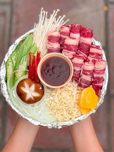 two hands holding a platter with meat and veggies on it, including rice