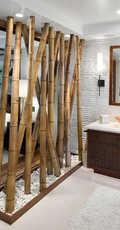 the bathroom is decorated with bamboo sticks and white pebbles on the floor, along with a large mirror