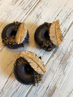 three black donuts with gold leaf decorations on them