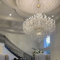 a chandelier hanging from the ceiling in a room with white walls and furniture