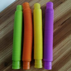 three different colored plastic cups sitting on top of a wooden table next to each other