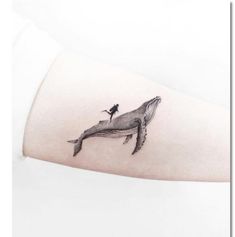 a woman's arm with a small whale tattoo on it