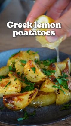 a person is dipping some lemon into potatoes on a plate with the title overlay reads greek lemon potatoes