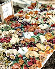 an assortment of cheeses, crackers and fruits arranged on a table with a sign