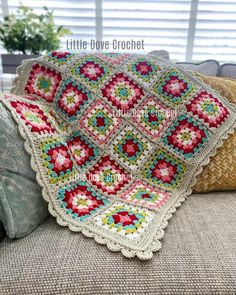 a crocheted granny blanket sitting on top of a couch next to a pillow