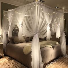 a canopy bed with white drapes and lights