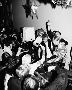 a group of people standing around each other in front of an electronic mixing console and recording equipment