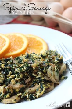 a white plate topped with meat covered in spinach next to sliced lemons and orange slices