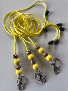 several yellow lanyards with leopard print beads and black metal snappers are on a white surface