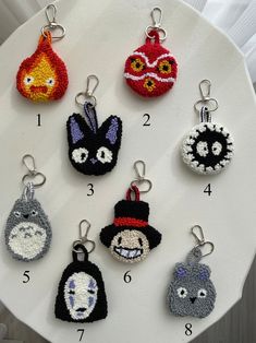 six keychains with different designs on them sitting on a white plate in front of a window