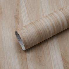 a roll of wood paper sitting on top of a wooden table next to a knife