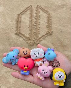 someone is holding out their hand with some cute little animals in front of the sand