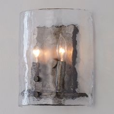 three lit candles are placed in an ice block on the side of a white wall