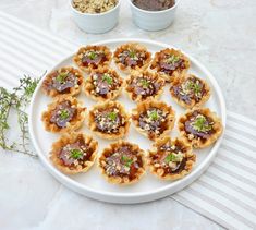 a white plate topped with mini desserts on top of a table next to bowls of toppings