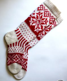 a pair of red and white knitted socks with snowflakes on the bottom