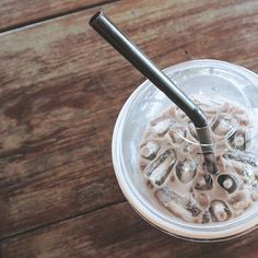 a glass with some food in it sitting on a wooden table next to a spoon