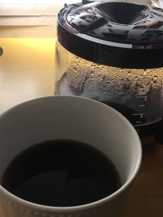 a cup of coffee sitting on top of a table next to an electric blender