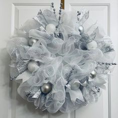 a white wreath with silver ornaments hanging on a door