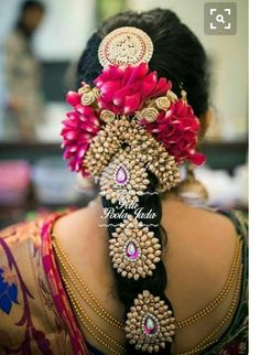 the back of a woman's head with flowers in her hair and jewelry on it