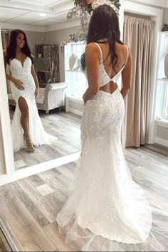 a woman in a wedding dress looking at herself in the mirror