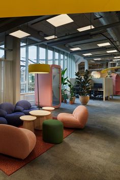 an office filled with lots of colorful furniture and large windowed area in the background