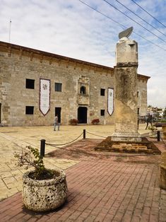 an old brick building with a clock tower in the center and people walking around it