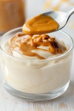 a spoon with caramel sauce on top of a dessert