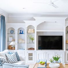 a living room filled with furniture and a flat screen tv mounted on a wall above a wooden coffee table