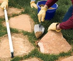 two people in yellow gloves are working on some rocks with shovels and pails