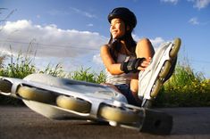 a woman sitting on the ground with her skateboard in front of her and an object behind her