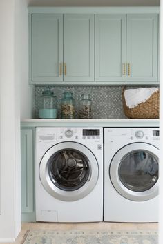 a washer and dryer in a laundry room with blue cabinetry on the wall