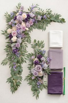 an arrangement of flowers and greenery laid out on a white surface next to a pair of scissors