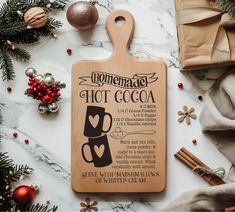 a wooden cutting board with hot cocoa on it next to christmas decorations and other items