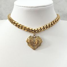 Our chunky gothic heart choker is beautifully handmade with a real premium feel. This stunning choker is available in a choice of two shades made with a detailed heart pendant accompanied by a gorgeous chunky chain. Chain type on silver and gold versions vary. Chain length is with a 28cm with 5cm extender. Chain thickness is 7mm. Silver colour material is pure stainless steel. Gold colour material is stainless steel with 14k gold plating. Vintage Choker Jewelry For Valentine's Day, Gothic Gold Heart Jewelry, Gold Heart Pendant With Chunky Chain, Metal Choker With Heart Charm And Pendant, Vintage Choker For Valentine's Day, Metal Heart Choker With Heart Charm, Gothic Heart Choker For Valentine's Day, Heart Charm Metal Choker With Heart Pendant, Metal Heart Pendant Choker With Heart Charm