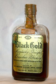 a bottle of black gold liquor sitting on top of a white tablecloth covered floor