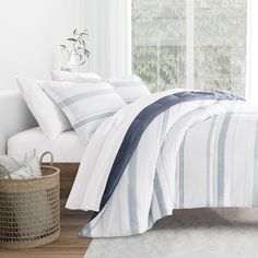 a white bed with blue and grey striped comforter