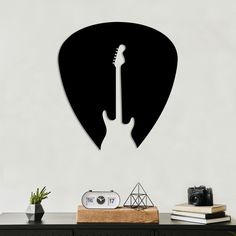 a guitar pick wall decal on the wall above a table with a clock and other items